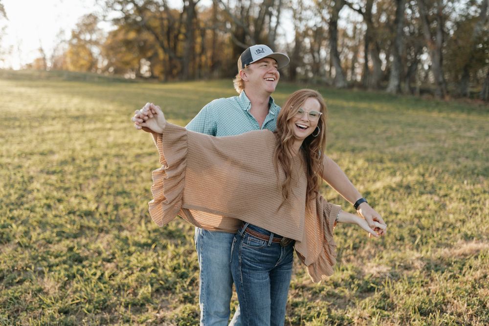 A playful moment between a couple as they enjoy time together in an autumn field.