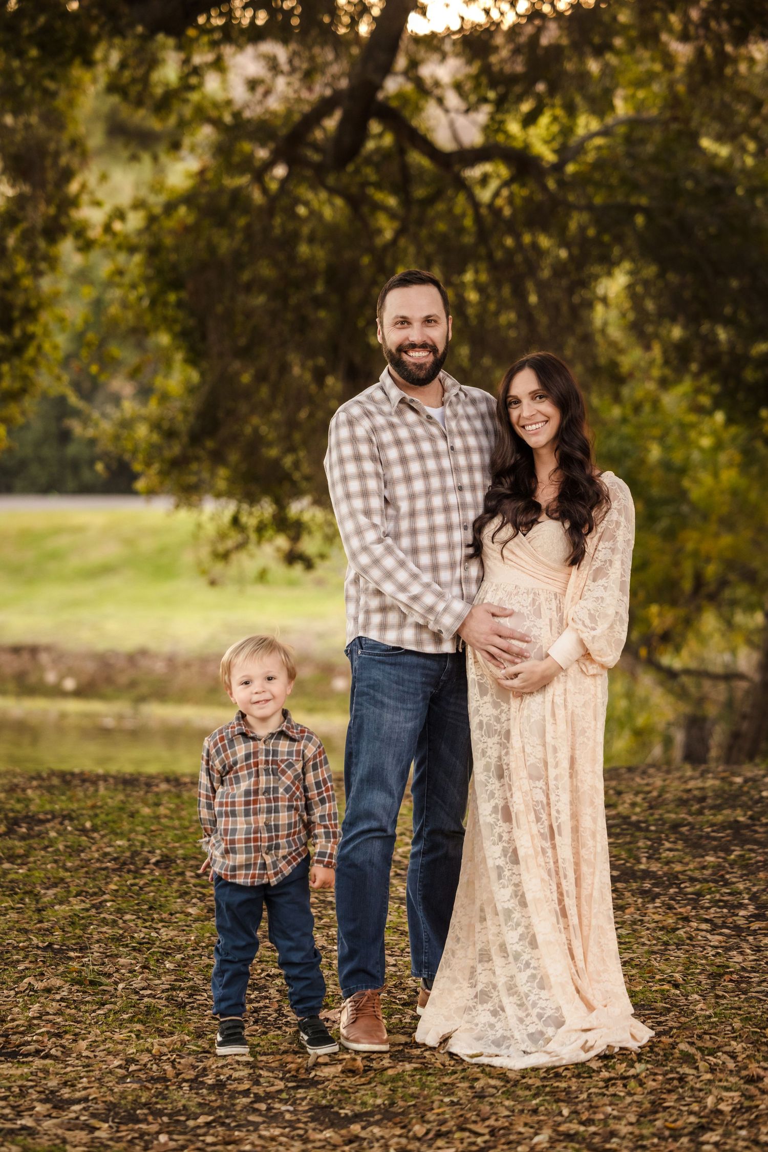 Family poses outdoors in coordinating plaid and lace outfits during golden hour autumn photoshoot.