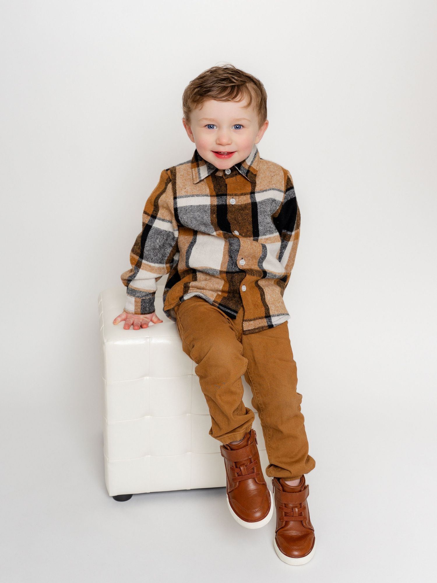 Photo of a little boy with red hair sitting on a pillow in family portrait photographer's studio in East Tennessee by Dandridge photographer