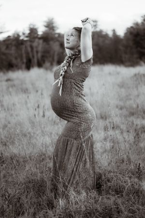Black and white maternity portrait series showing a flowing dress in a natural meadow setting.