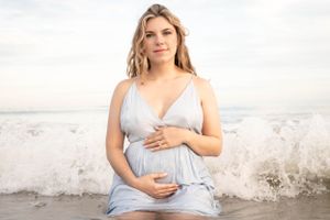 Serene beachside maternity photos with soft lighting and gentle waves in the background.