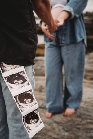 Close-up of ultrasound photos being held while standing on rocky beach.