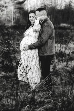 Black and white maternity photos showing tender moments between a couple in nature.