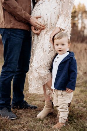 Candid family moments captured during maternity session in natural outdoor setting.