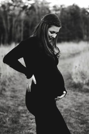 Artistic black and white silhouette photos of a pregnant woman in an outdoor setting.