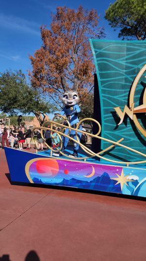 Judy Hopps character from Zootopia waves from a colorful parade float at Disney World theme park.