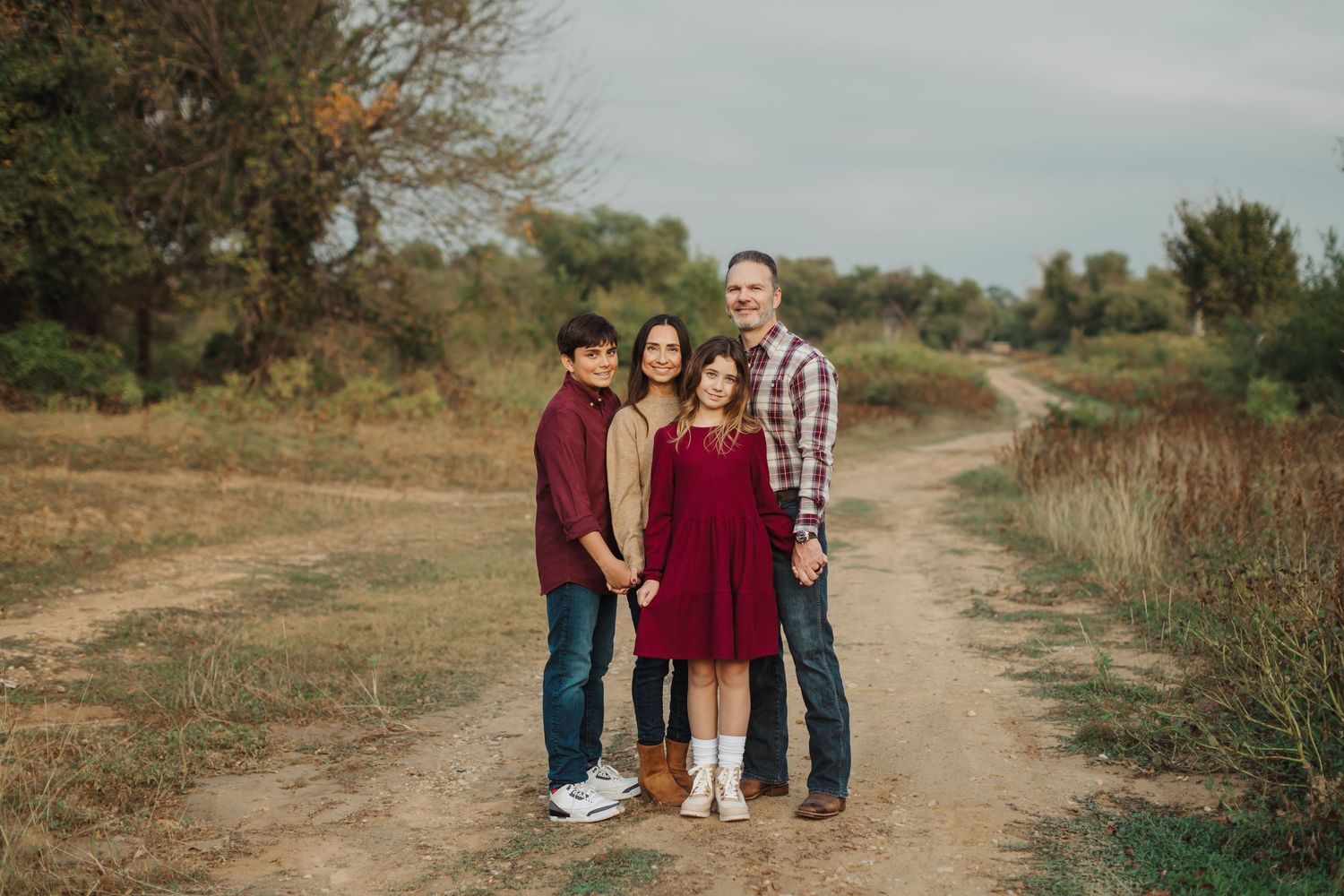 Family photoshoot on a scenic dirt path during golden hour in a rural setting.
