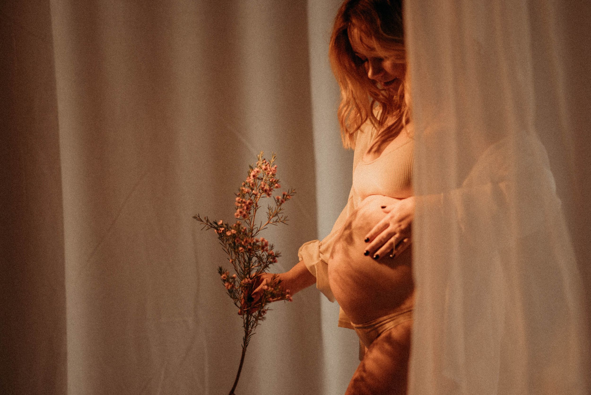 Intimate maternity boudoir session with dramatic lighting and shadows.