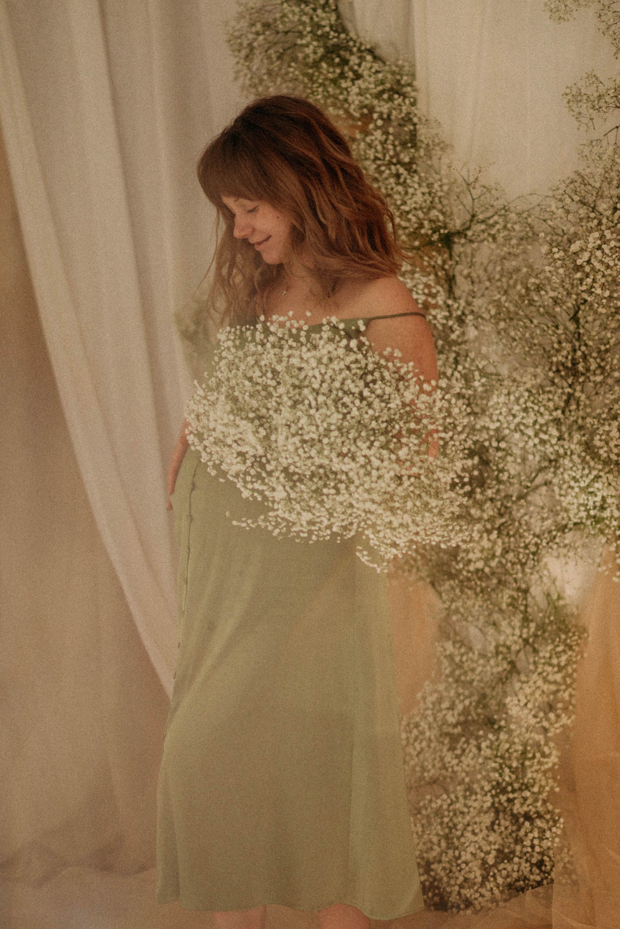 Romantic maternity portraits with baby's breath flowers in soft natural light.