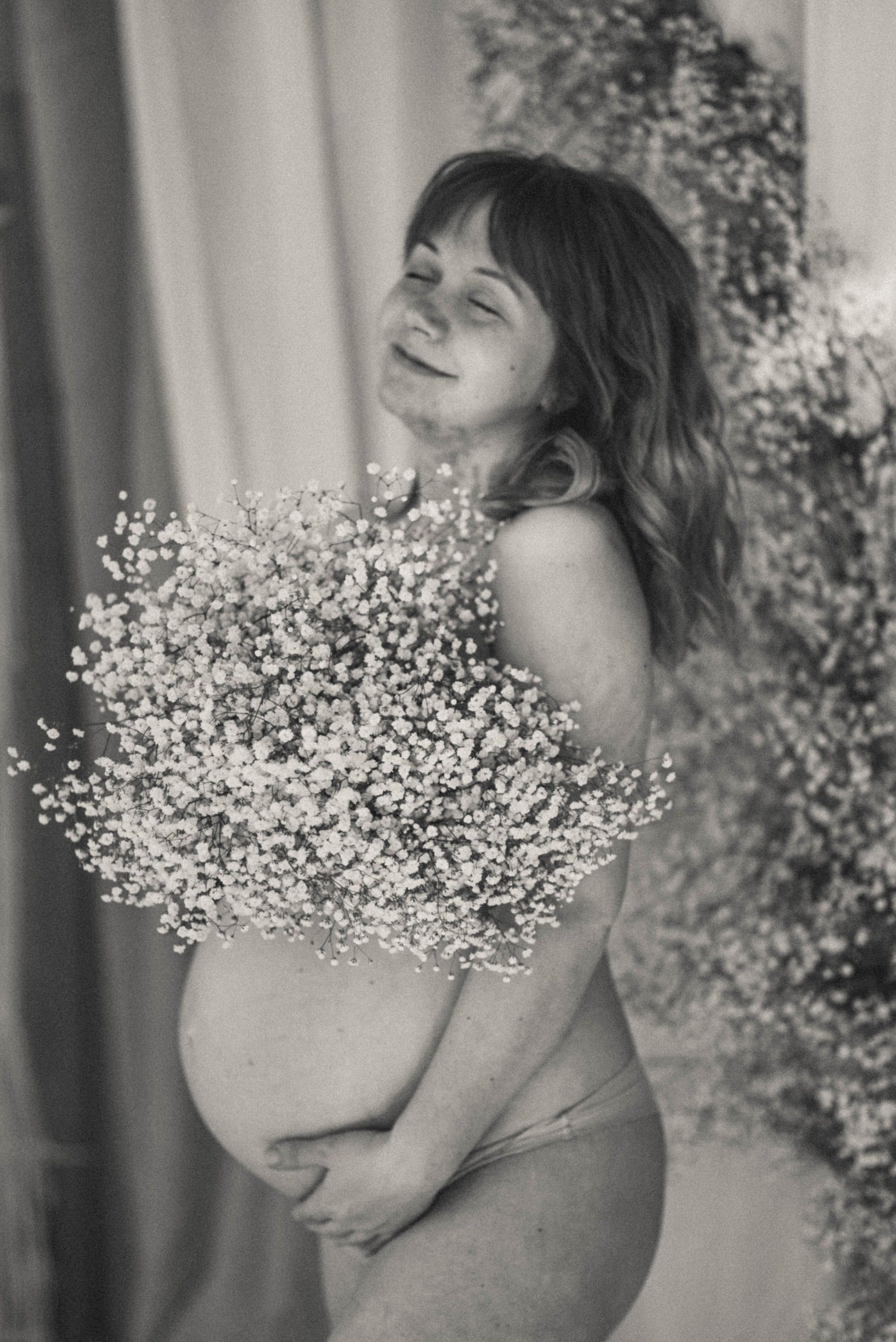 Artistic black and white maternity portrait with baby's breath flowers.