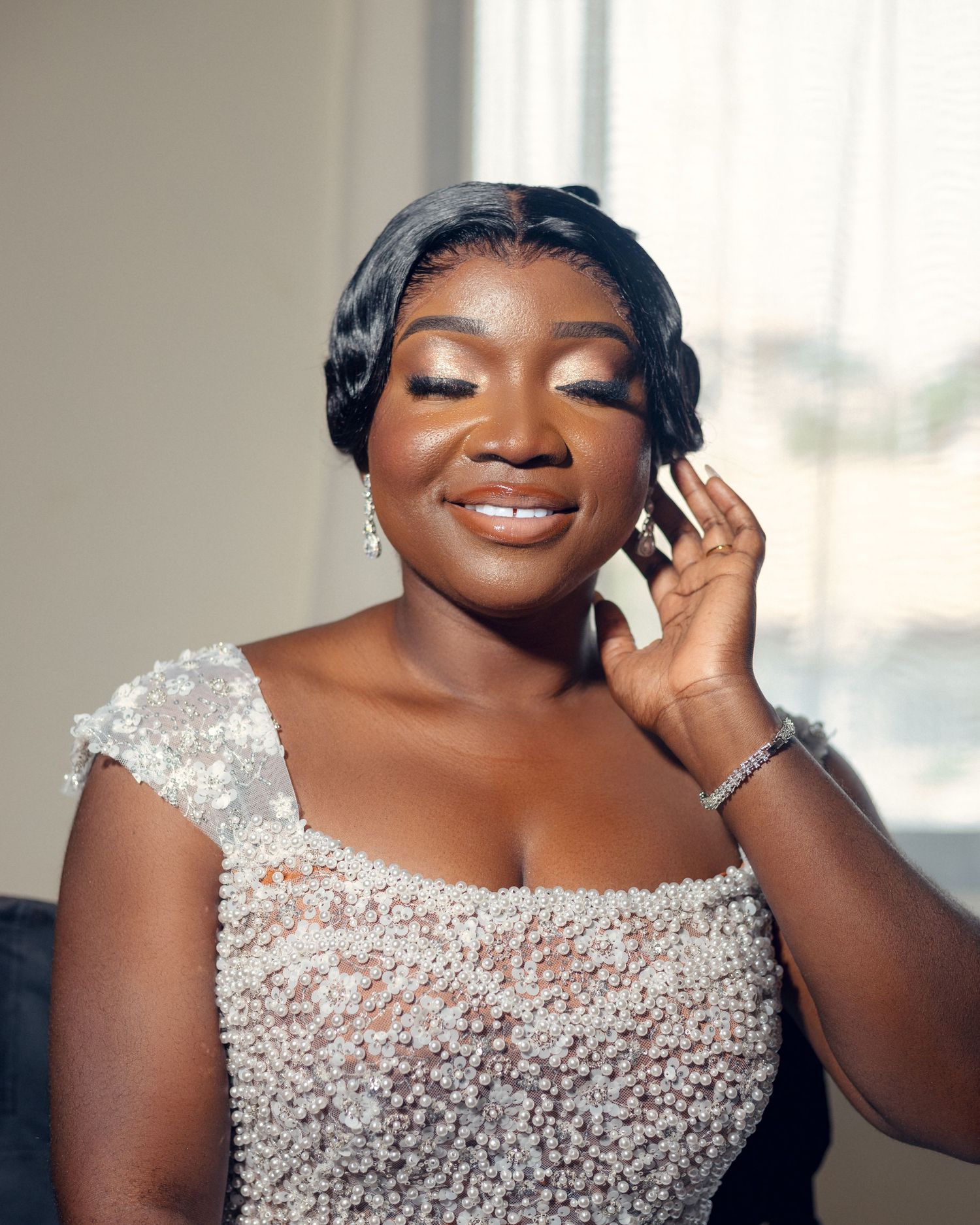 Close-up of bride wearing sparkling white beaded wedding dress with elegant makeup and jewelry.