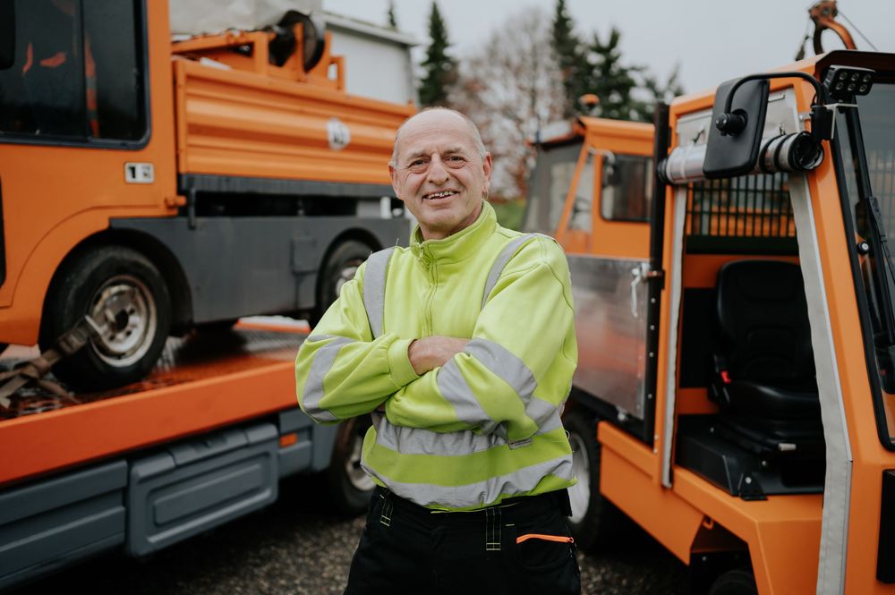 Orangefarbenes Nutzfahrzeug mit Bediener im Vordergrund.