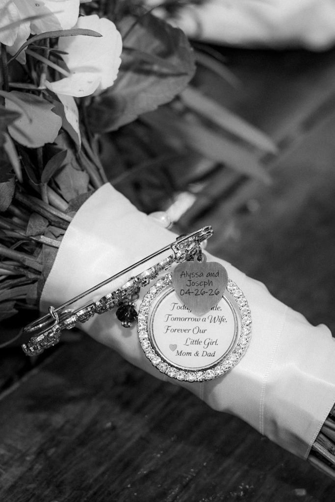 Black and white wedding bouquet with a sentimental charm brooch reading Today Tomorrow's Wife Forever Our Little Girl, Mom and Dad.