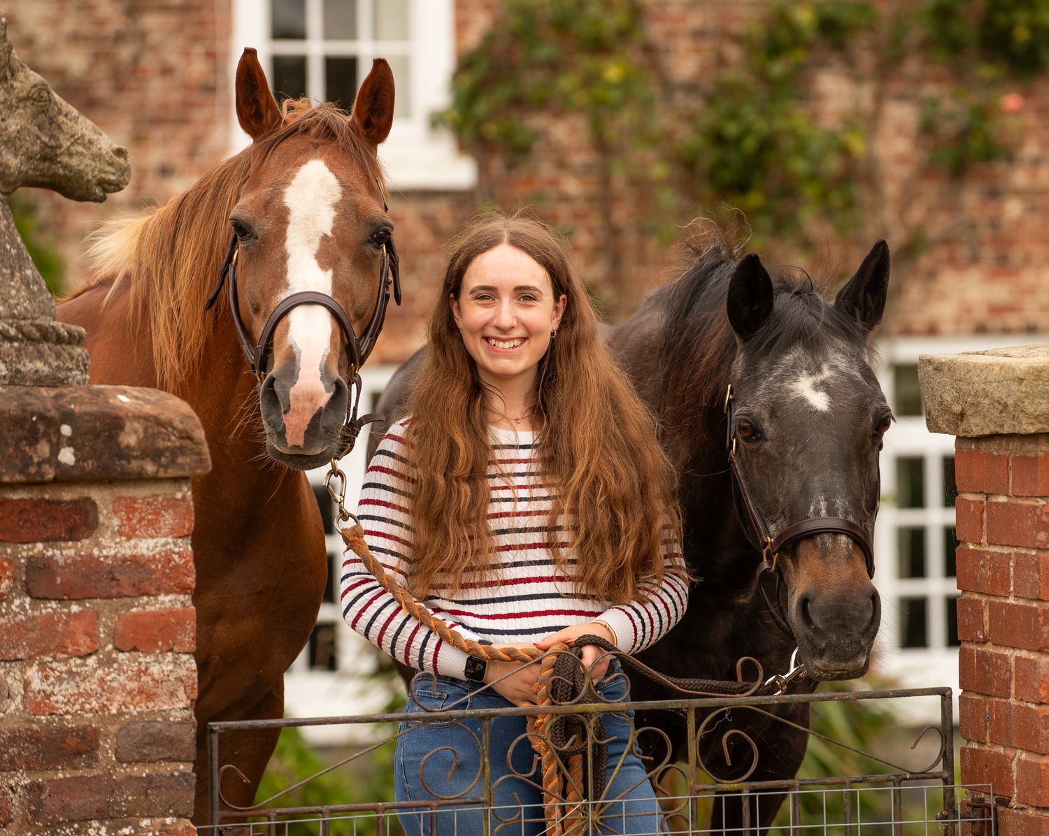 A brown horse and person stand together in a woodland clearing filled with blooming bluebells.
