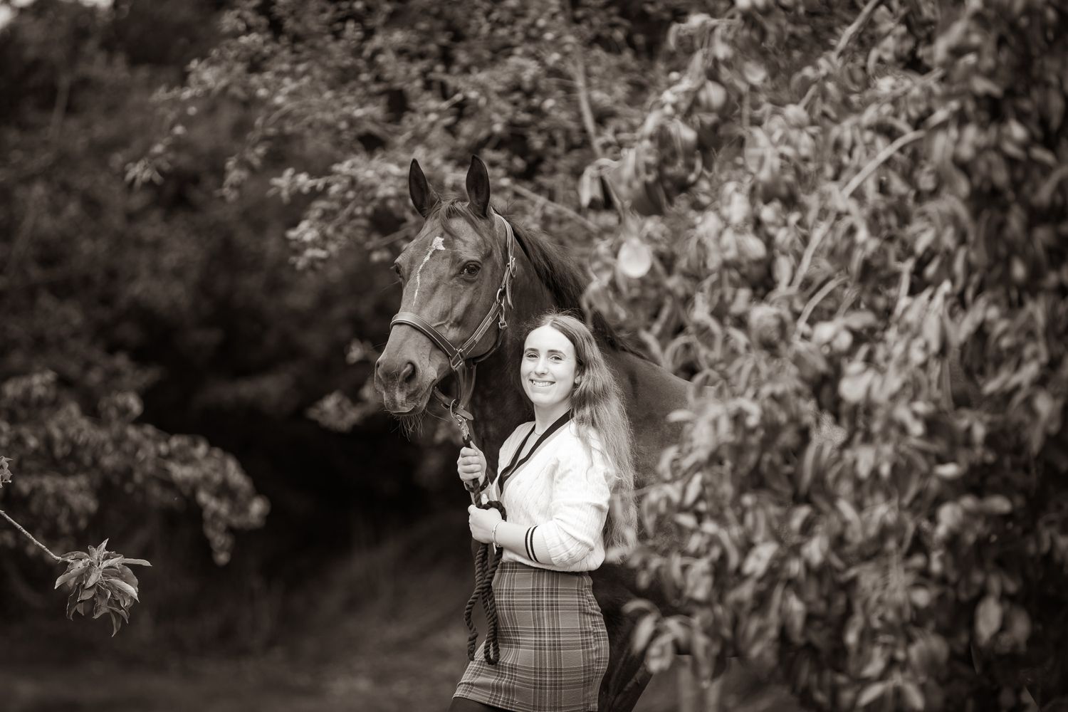 A beautiful black and white paint horse stands with a person on a sunny autumn day outdoors.