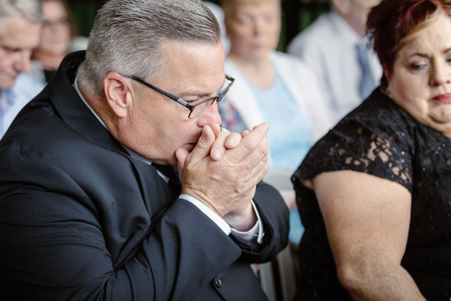 A row of people in formal attire seated at a table during an emotional moment at an event.