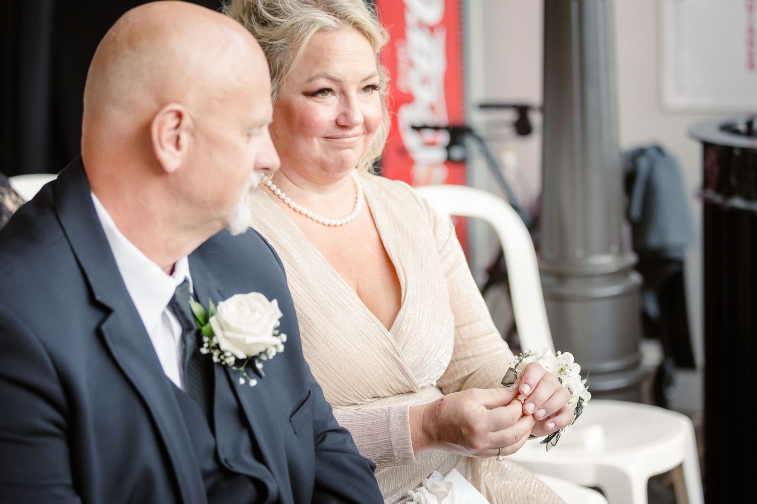 Guests in formal wear seated at a wedding reception table with white floral centerpieces.
