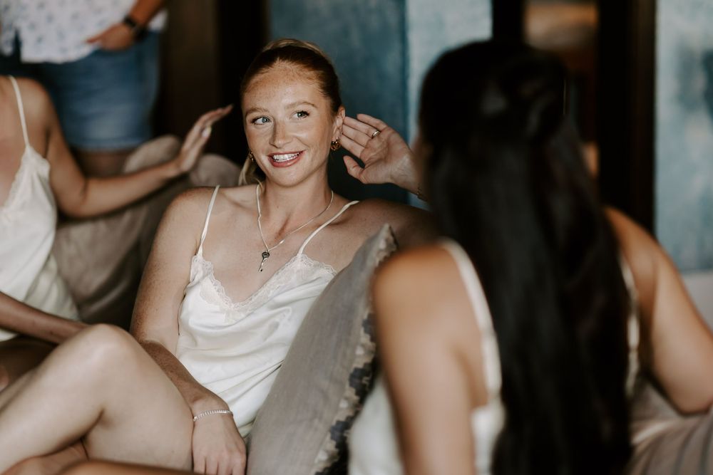 Wedding party getting ready together in a candid moment captured in soft lighting.