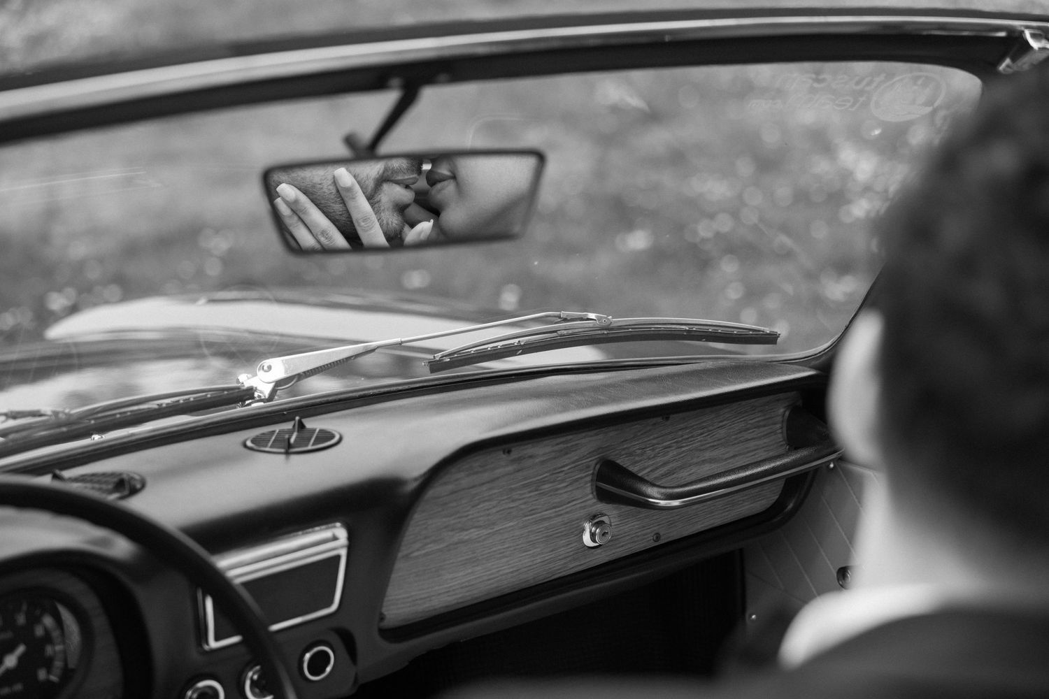 Interior view of classic car dashboard and steering wheel in black and white.