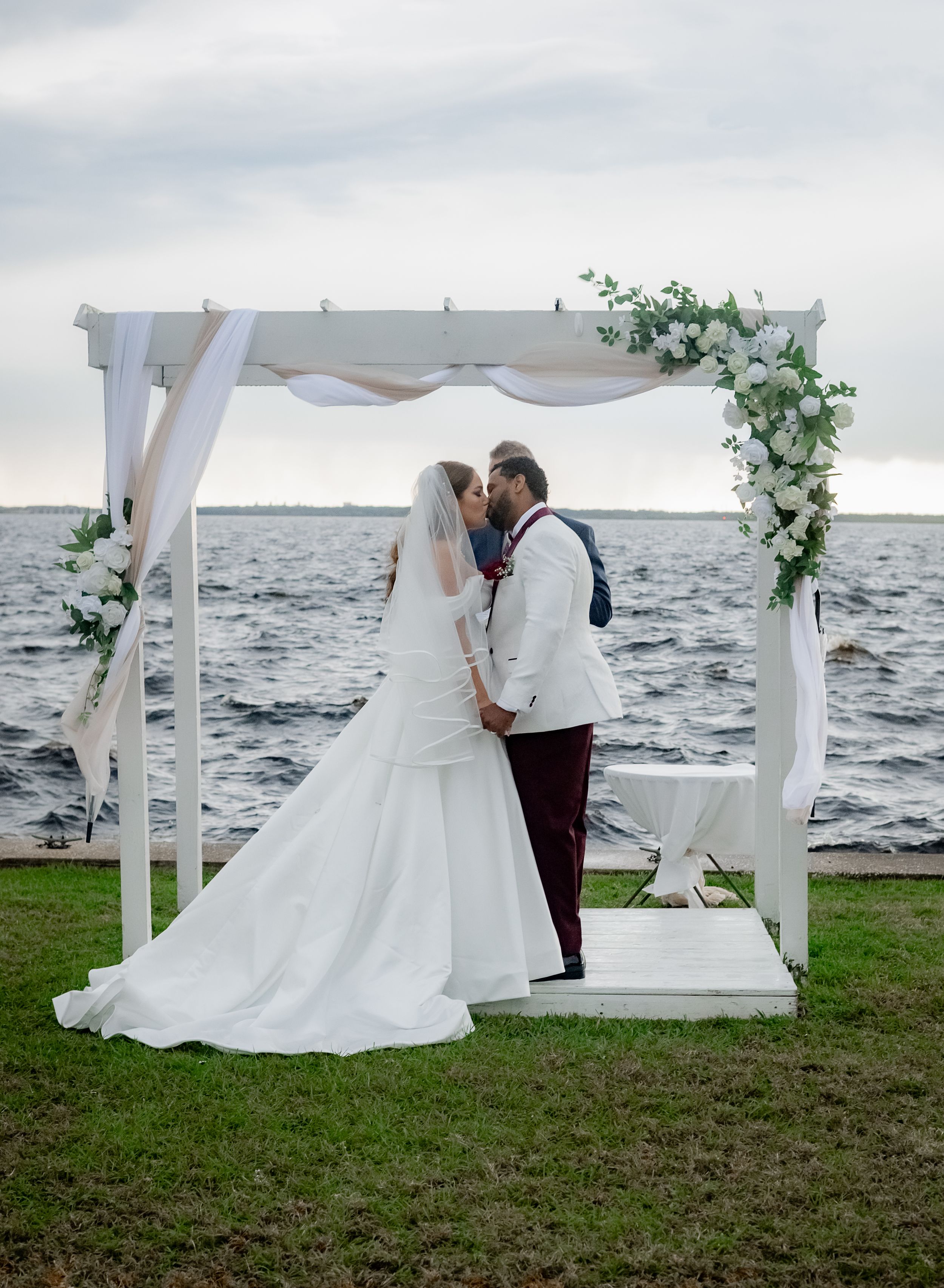 Romantic wedding couple shares intimate moments under white canopy by stormy ocean across multiple photographs.