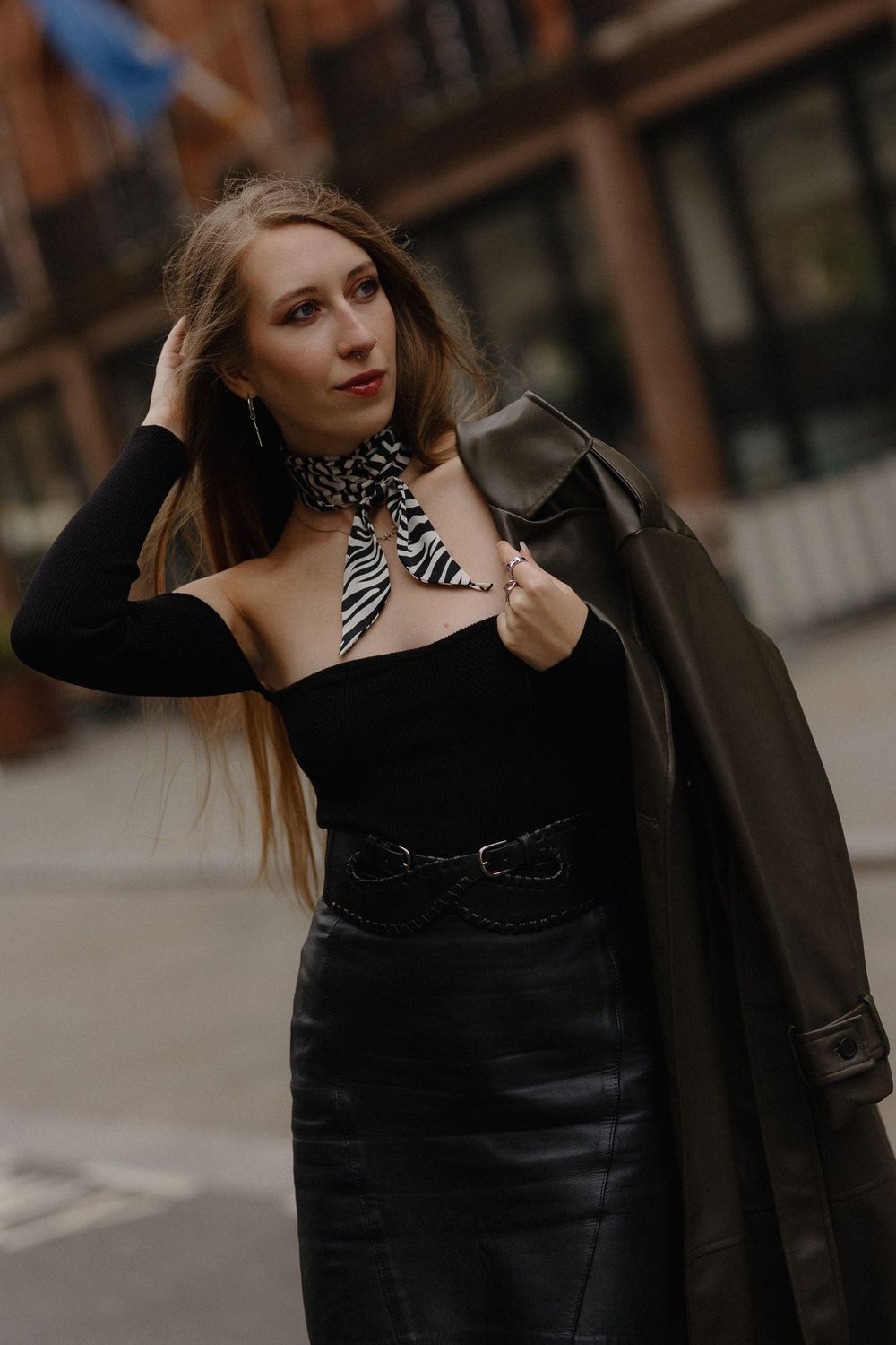 A person in black clothing poses outdoors against an urban backdrop in a series of stylish fashion portraits.