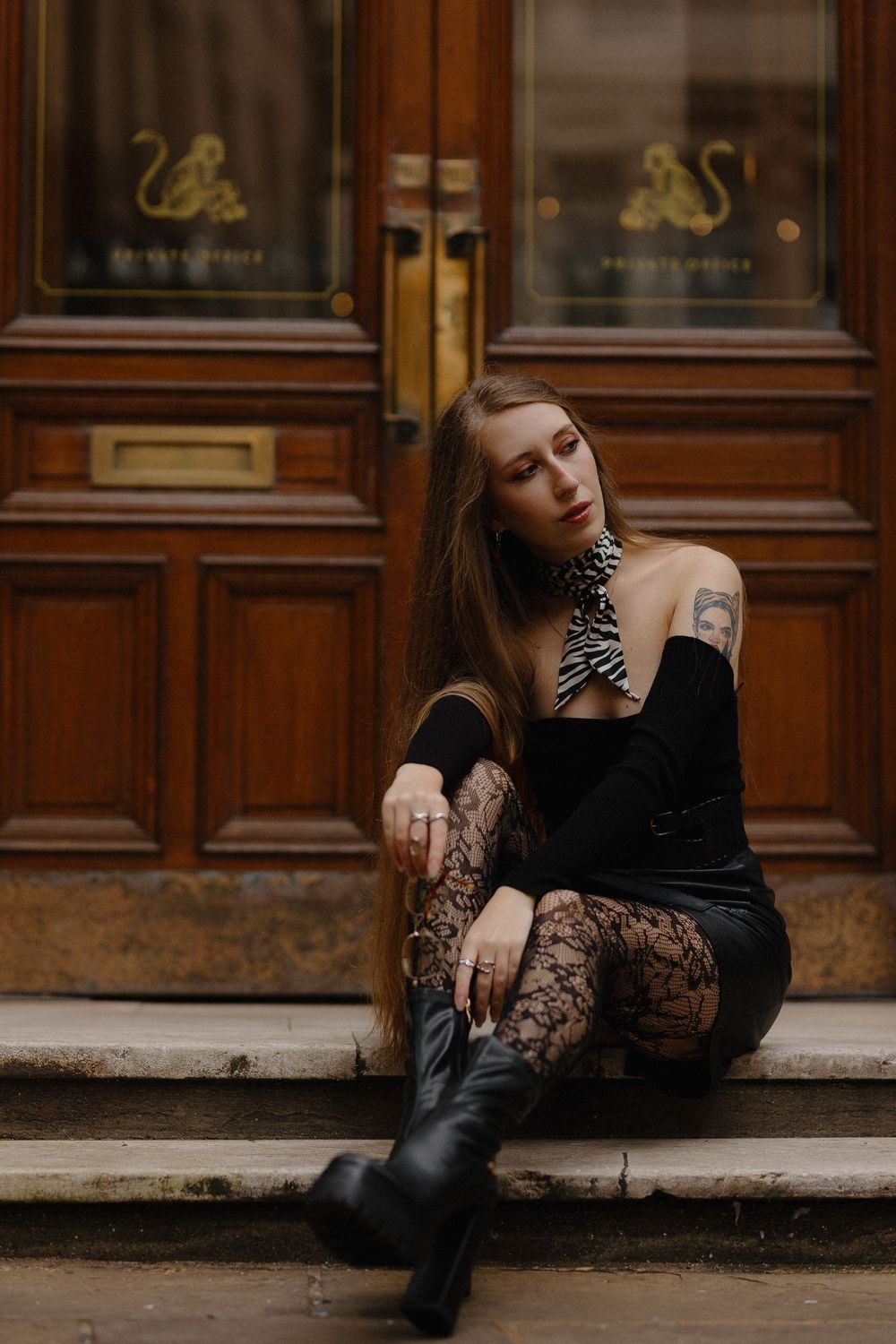 Fashion photo series showing a person in black dress and boots posing on stone steps against wooden doors.