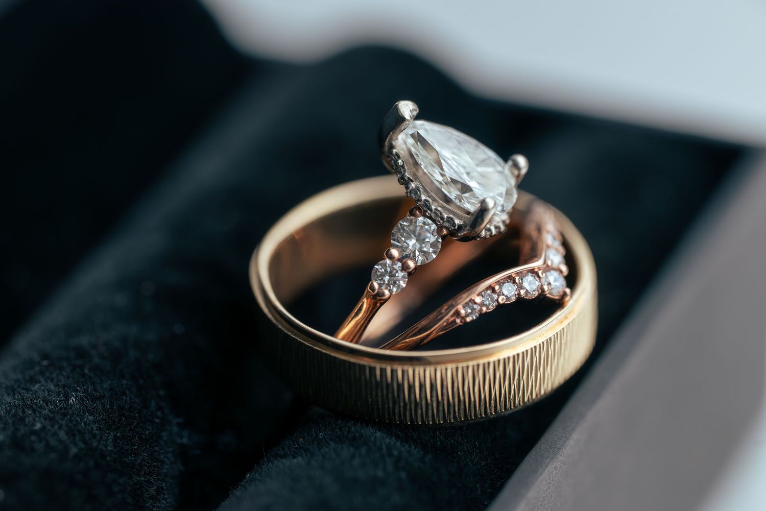 Close-up photo of a sparkling diamond engagement ring on a dark reflective surface.