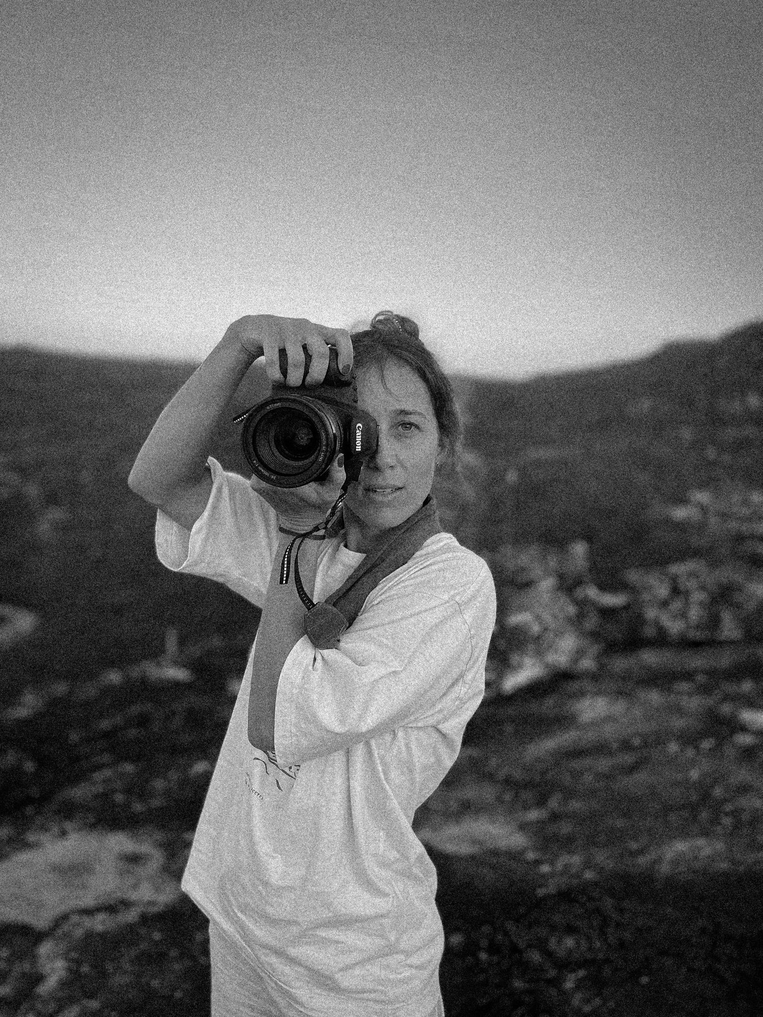 Black and white image of someone taking photographs in a natural landscape.