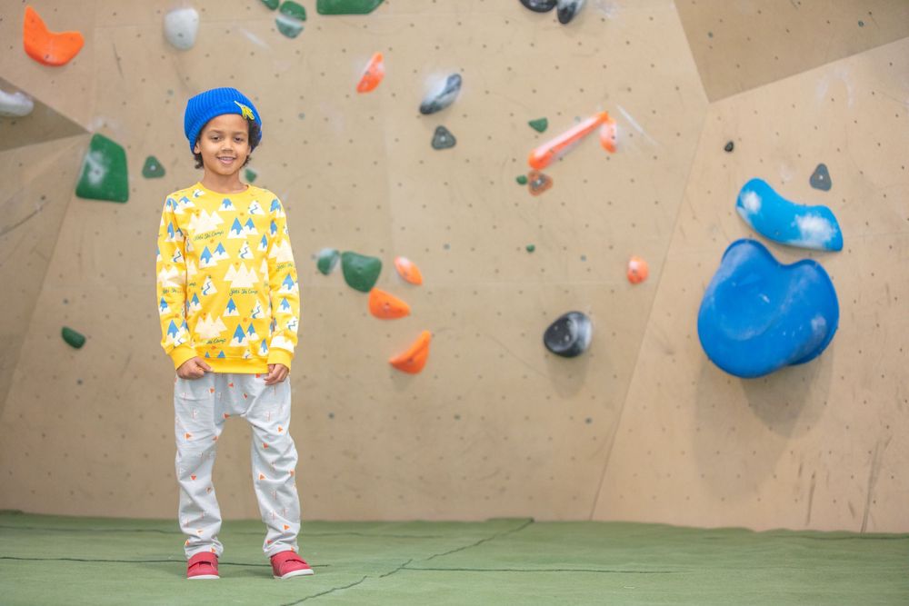 Kids climbing on an indoor rock wall with colorful holds.