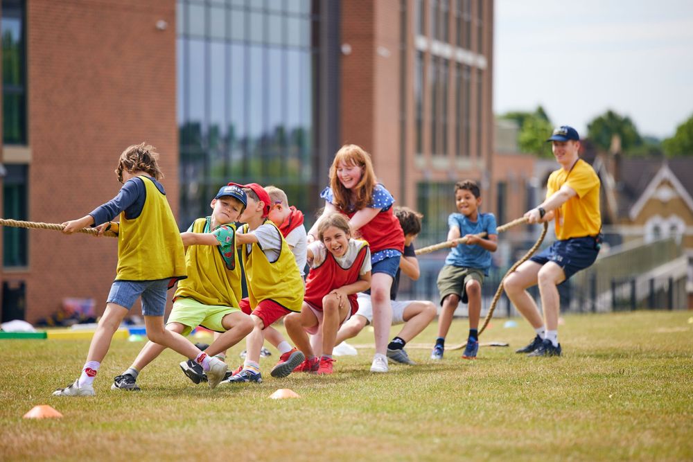 Group of students stretching and exercising together on a sunny day outside their school.