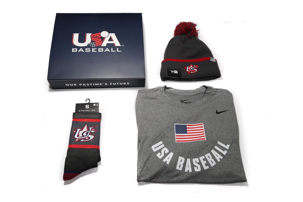 USA Baseball gift set featuring Nike t-shirt, pom beanie hat, and branded athletic socks in navy box.