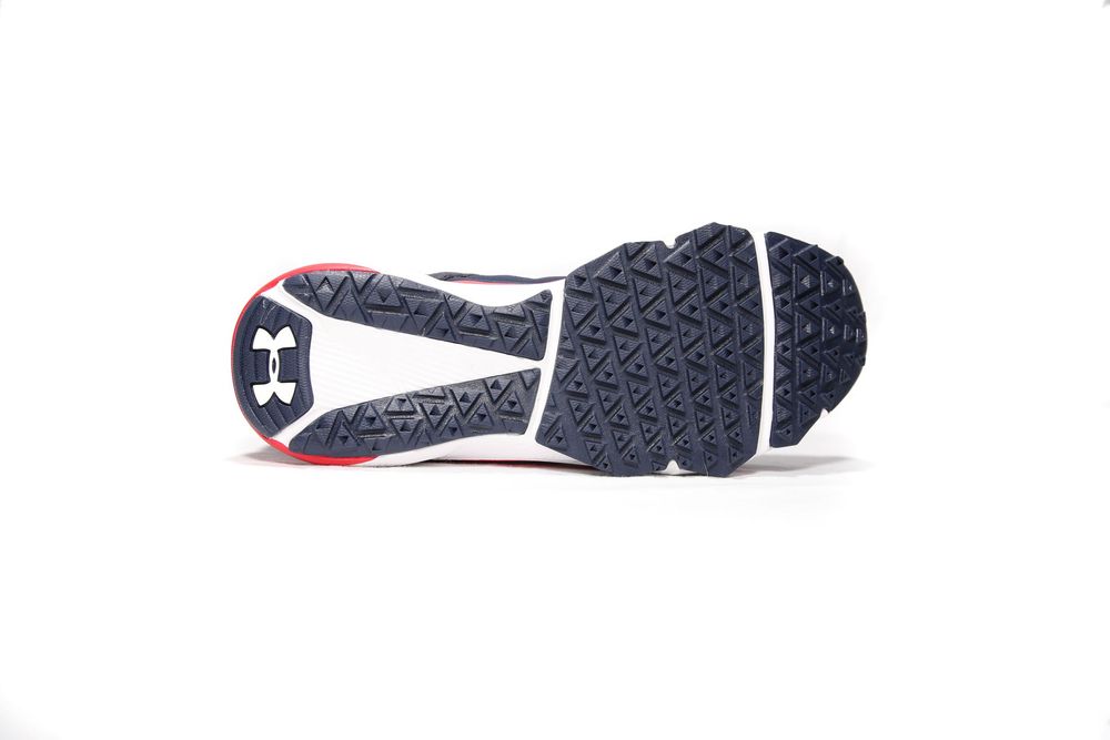 Bottom sole view of Under Armour navy and red athletic shoe showing traction pattern and logo.