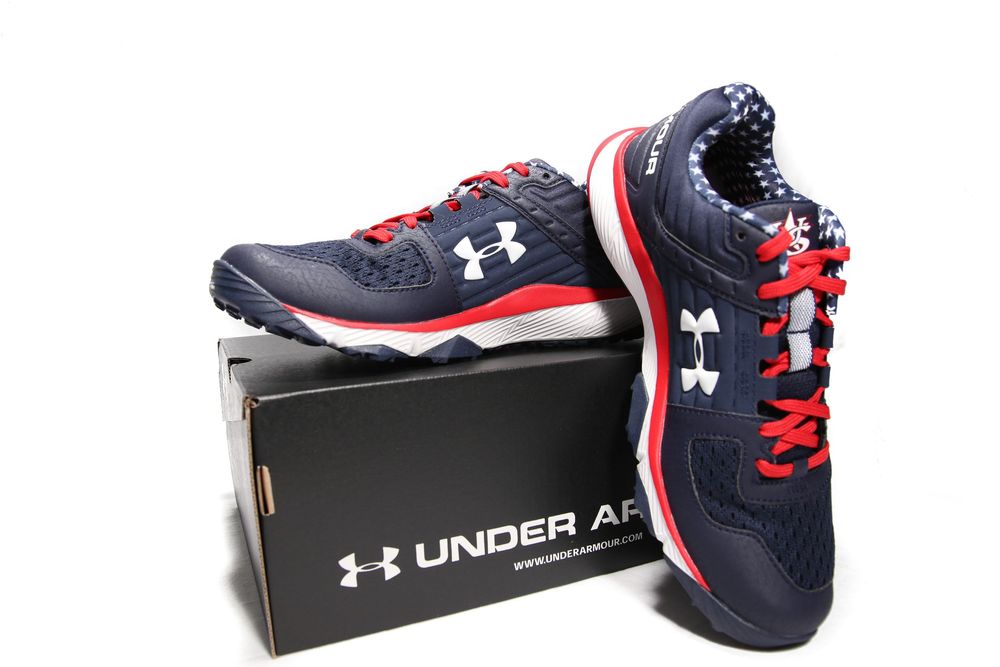 Pair of Under Armour navy red and white baseball training shoes displayed on branded shoe box.