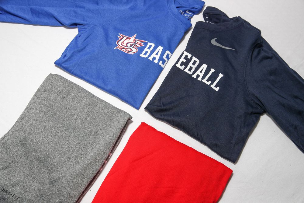 Blue and navy Nike Baseball long-sleeve shirts with gray and red athletic shorts.