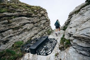 A group of hikers navigate a steep rocky mountain trail with climbing gear and safety equipment.