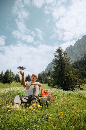 A couple relaxes in a scenic Alpine meadow filled with wildflowers beneath towering mountain peaks on a sunny day.