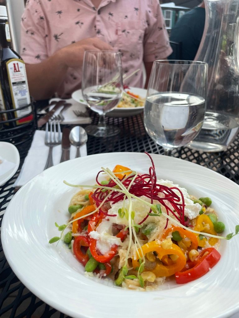 Vibrant citrus salad with microgreens, red cabbage, and edible flowers served on white plates at an upscale restaurant.