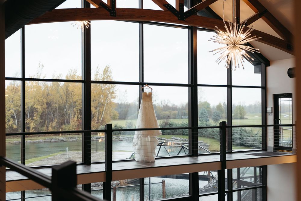 Modern restaurant interior with floor-to-ceiling windows overlooking a river and natural scenery at sunset.