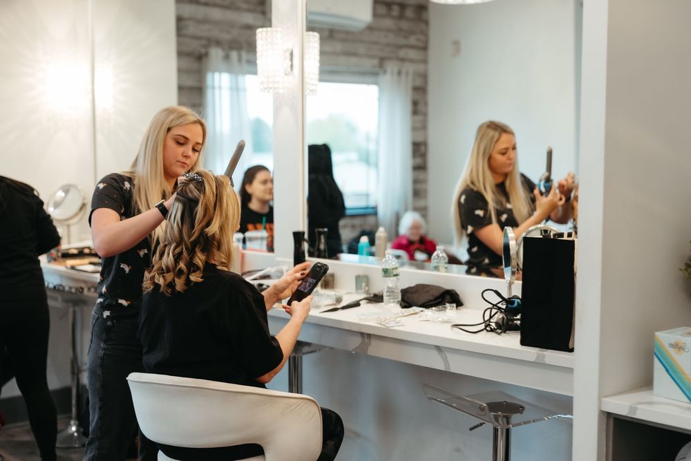 Hair and makeup artists work in a bright modern salon with wood accent walls.