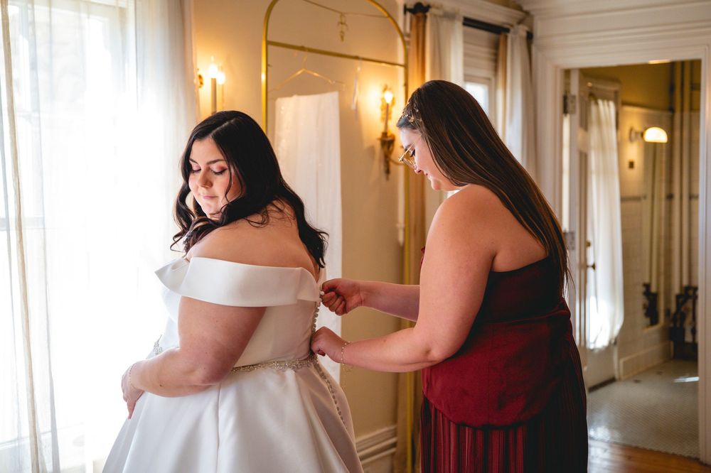 A wedding dress fitting scene in a sunlit room with warm decor and elegant details.