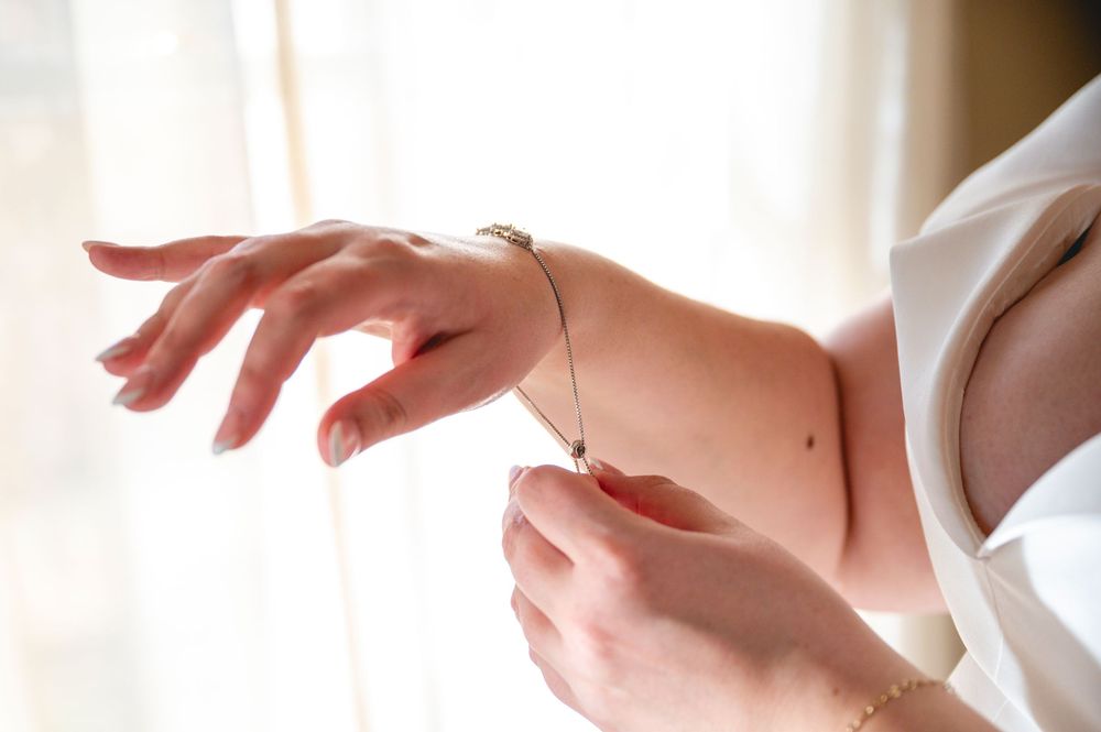 Close-up shot of hands being moisturized with white cream or lotion against a light background.