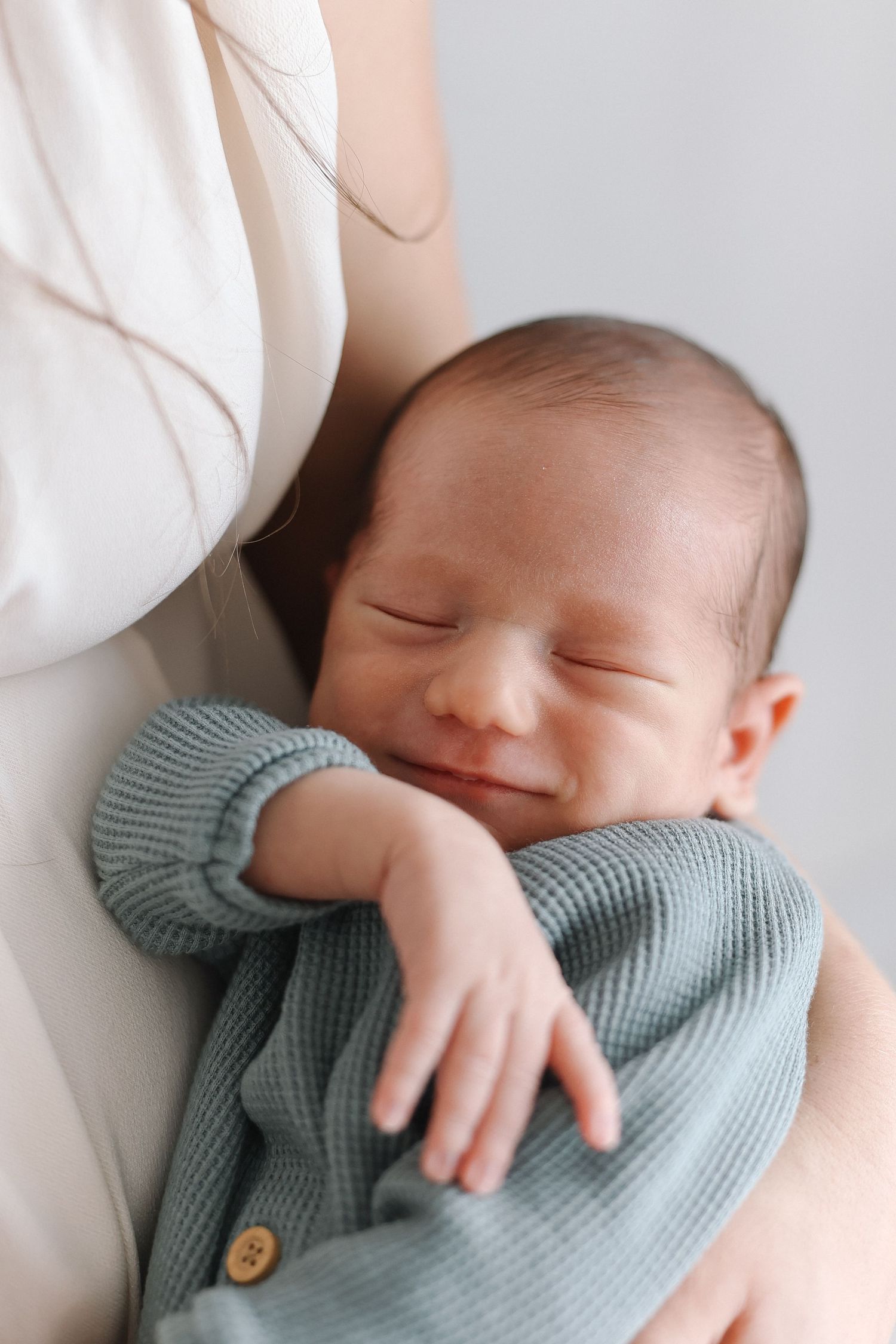 Newborn photos highlighting baby’s soft face smiling and his hair and delicate features in Orange County