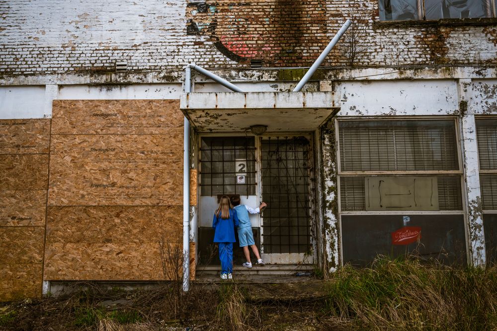 Twee kinderen ontdekken een verlaten gebouw tijdens een creatieve communieshoot – authentieke storytelling door Bart Boodts Photography