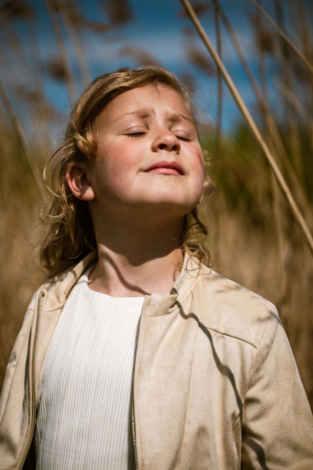 Meisje met gesloten ogen geniet van de zon tijdens een communie fotosessie in de natuur – pure fotografie door Bart Boodts