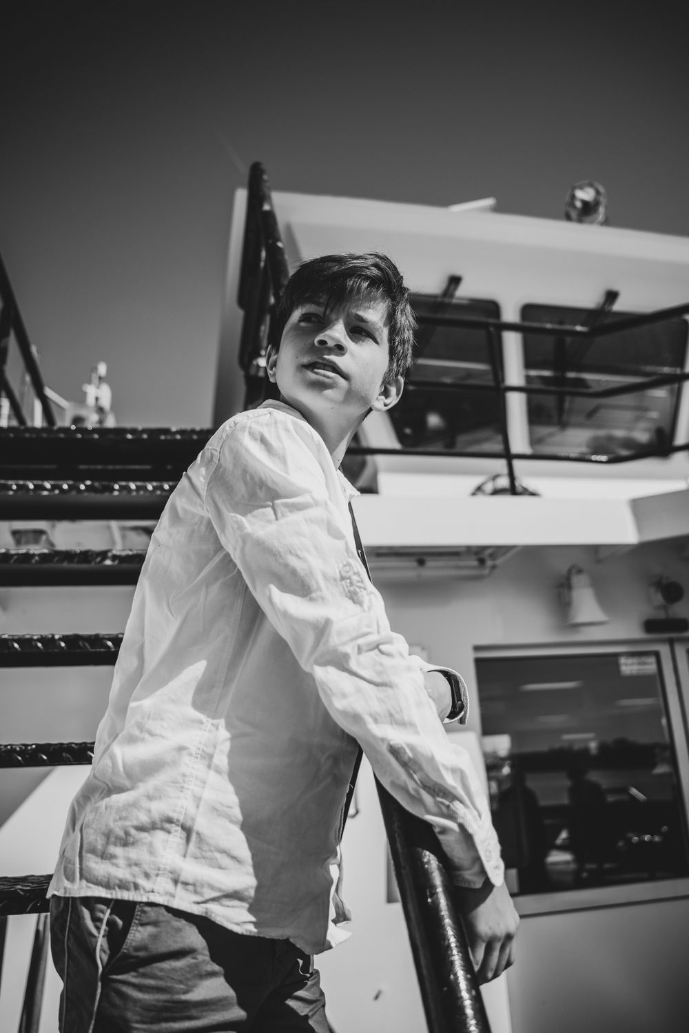Jongen in wit hemd op een boottrap aan de Schelde – stijlvol en tijdloos communieportret door Bart Boodts