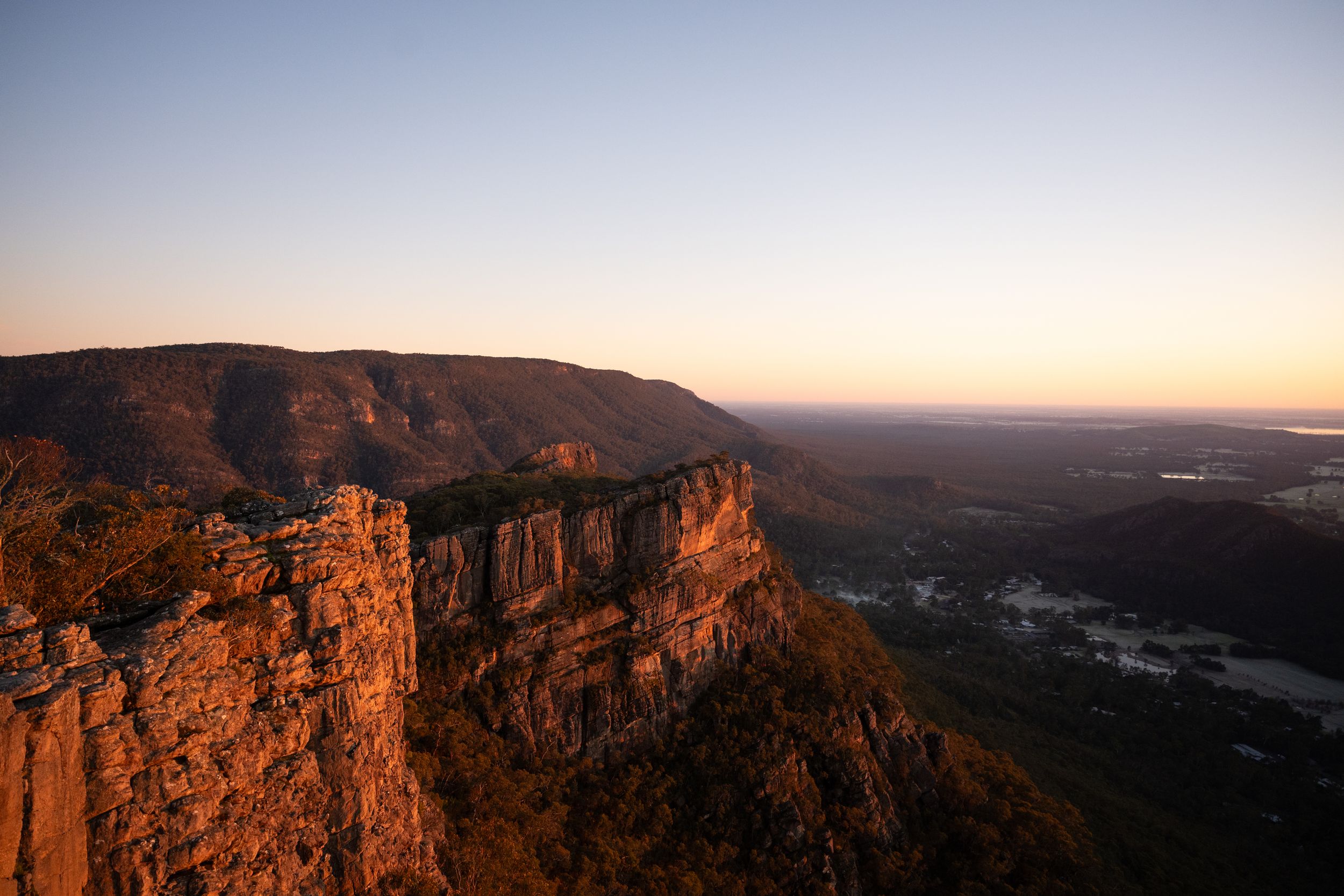 Dramatic sandstone cliffs at golden hour sunset overlooking vast plains from Grampians mountain ranges Victoria