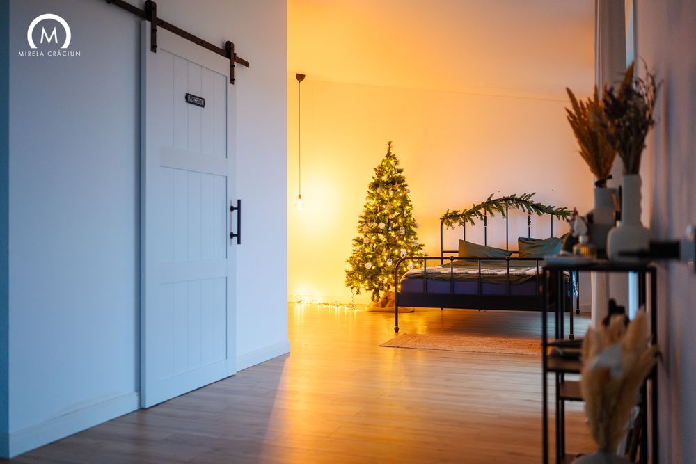 Illuminated Christmas tree glows in a modern room with sliding barn door and hardwood floors.