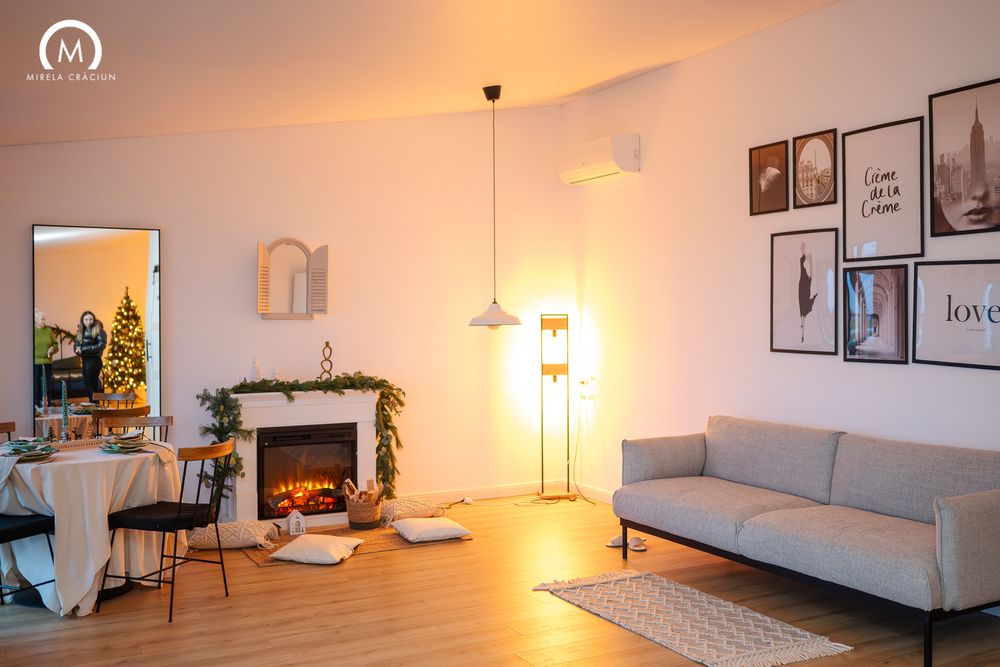 A bright and modern living room with white walls, pendant lights, and minimalist decor in warm ambient lighting.