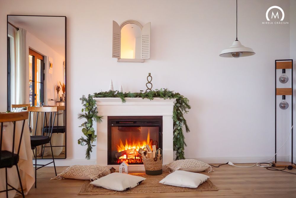 Cozy minimalist living room with fireplace, white cushions, and hanging plants creates a warm and inviting atmosphere.
