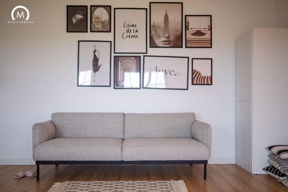 Modern living room interior with gray sofa, framed wall art, and minimalist decor in neutral tones.